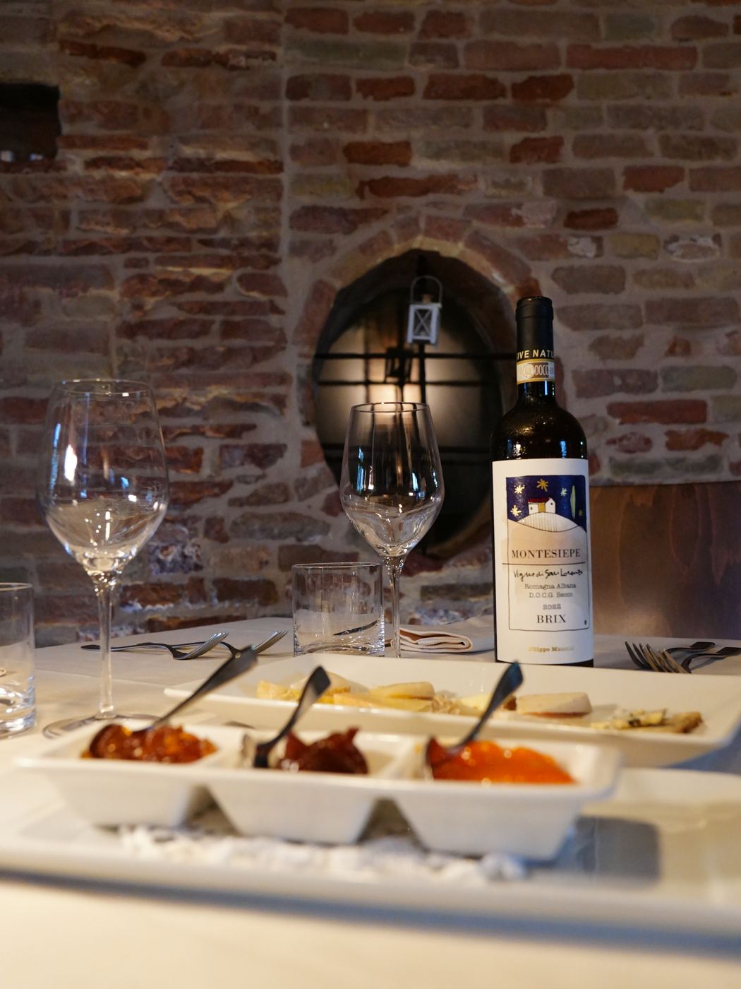 Assaggi in tavola e una bottiglia di Montesiepe Brix nella sala in mattoni